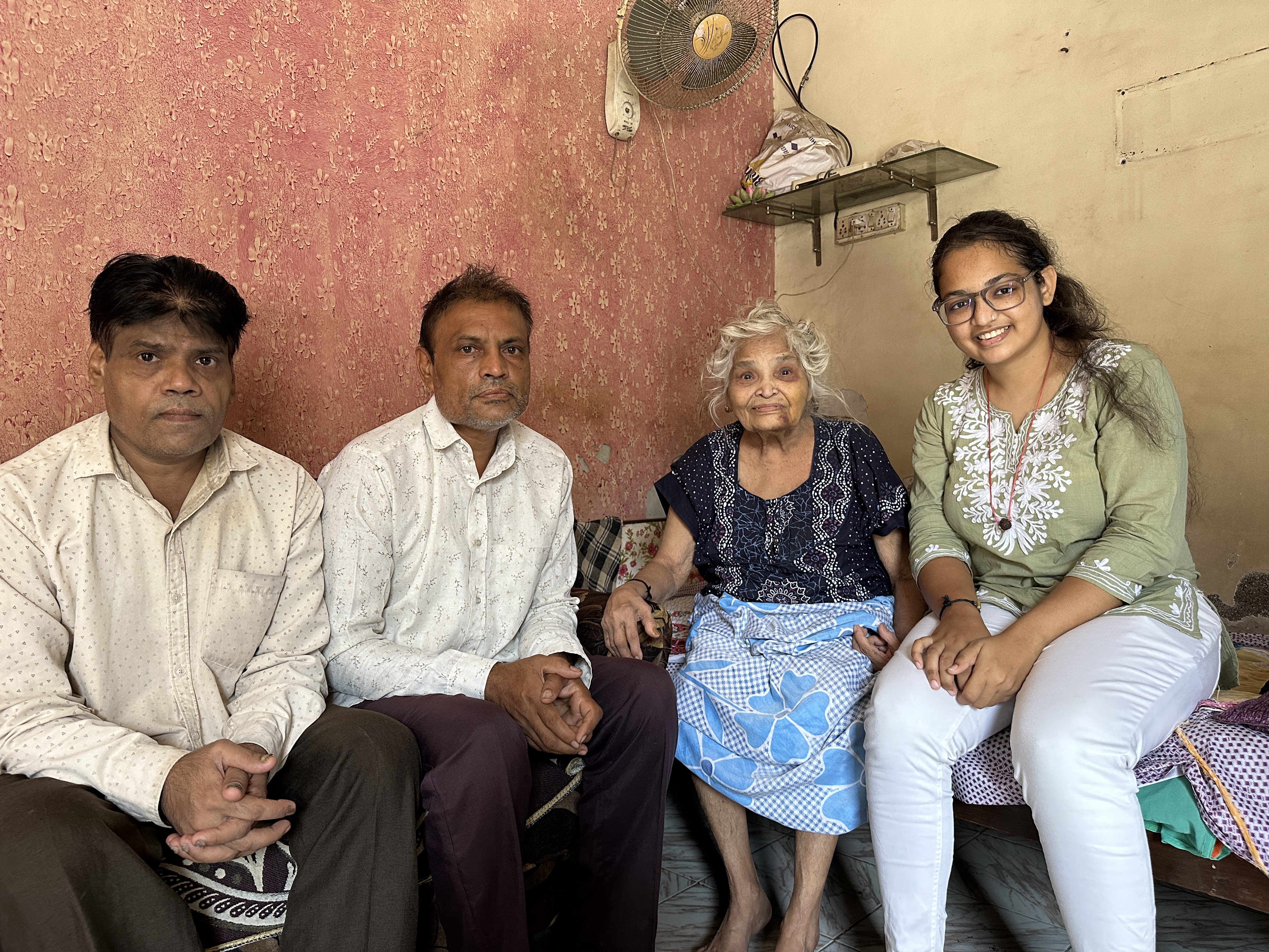 Quatre personnes sont assises ensemble dans le coin d’une pièce. Reena et sa grand-mère sourient, les deux oncles de Reena sont assis à côté d’elle. Surat, Inde (2024)