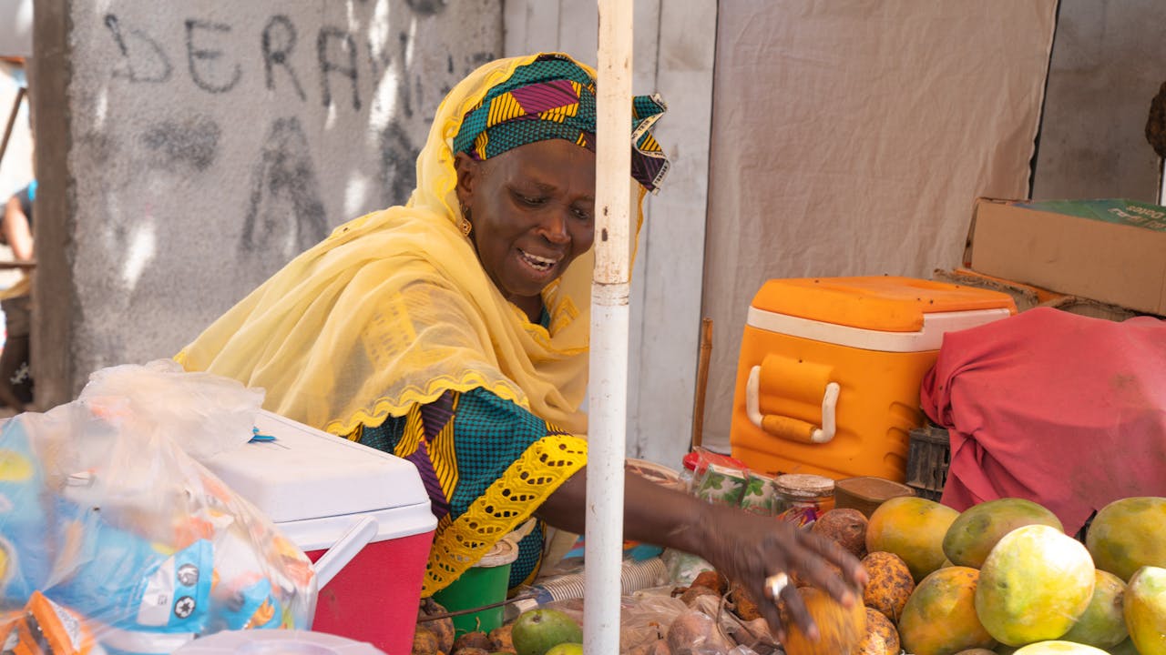 Astou Gningue lays out mangoes on her fruit stall. Pikine, Senegal. (2024)