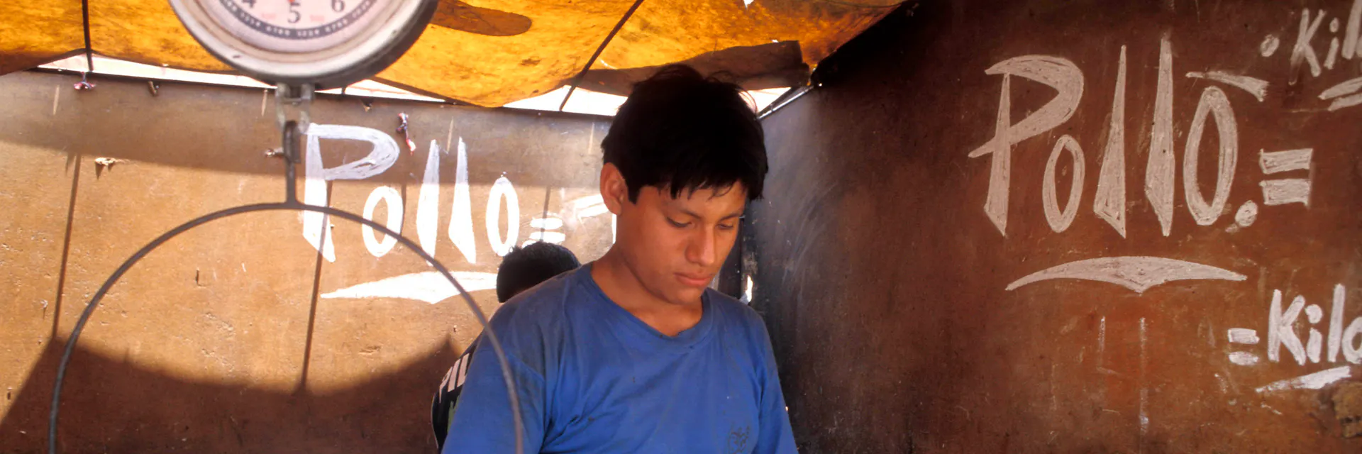 Un joven prepara pollo en una pollería del mercado (Lima, Perú).