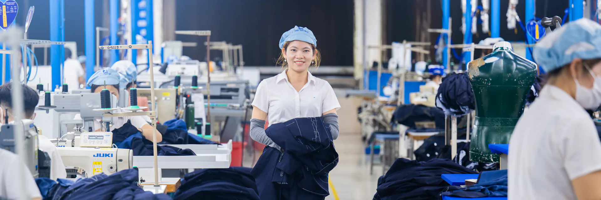 Jeune ouvrière marchant et souriant parmi les travailleurs de l'entreprise Garment 10, Hanoi, Viêt Nam.