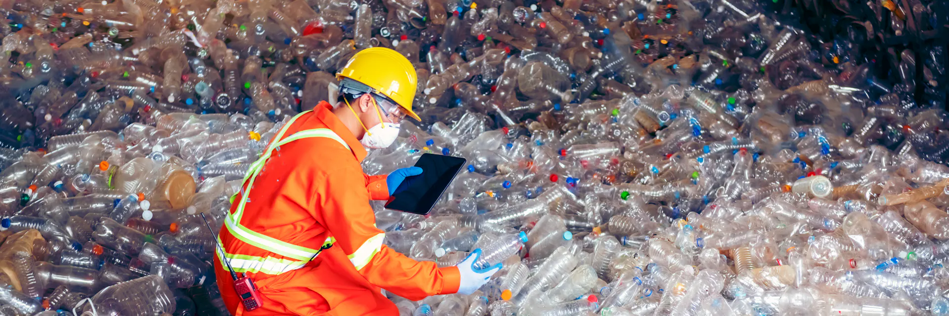 Un homme en uniforme orange examine des bouteilles dans un centre de recyclage. Industrie du recyclage.