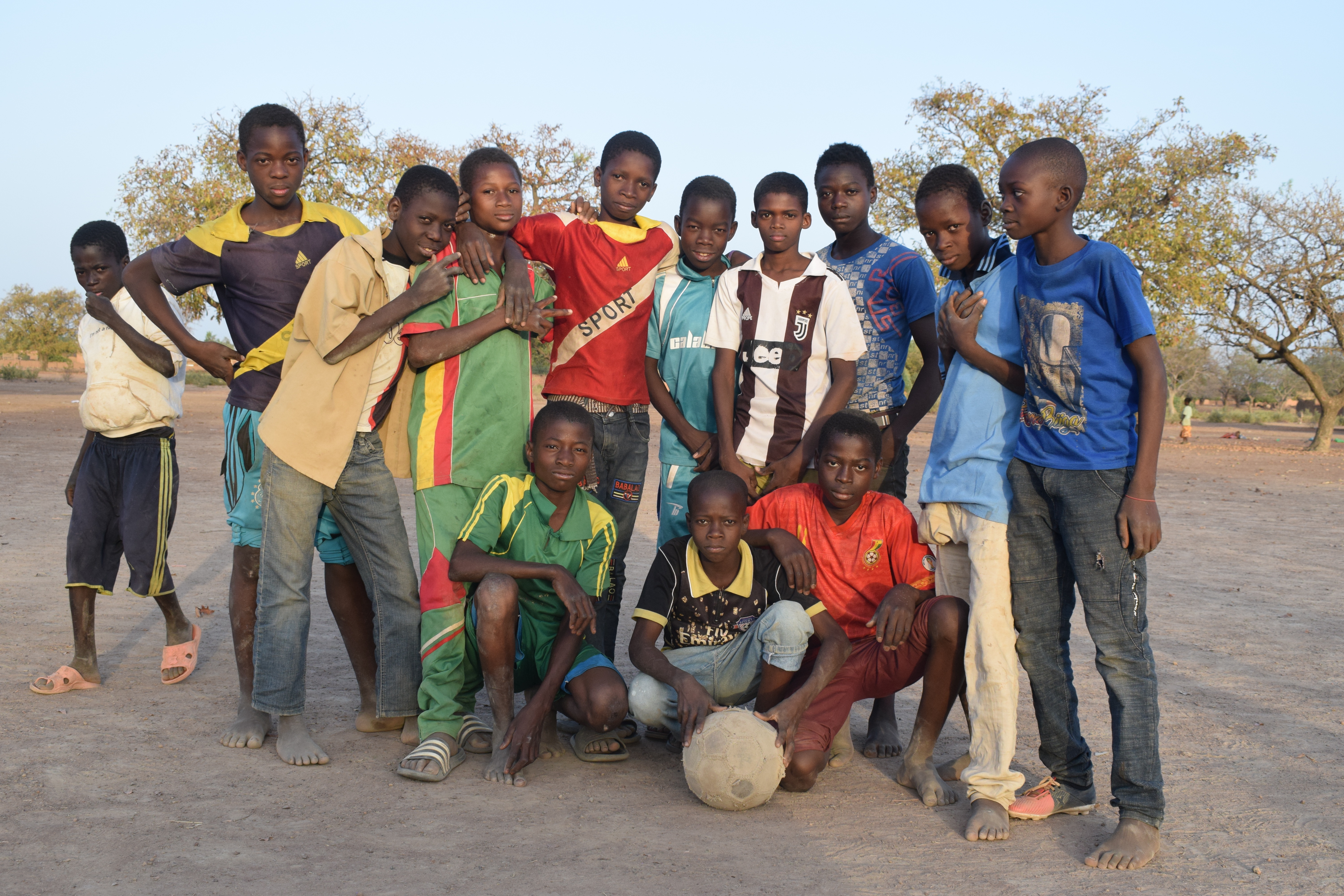 Domboué Nibéissé poses for the camera outside with a group of boys.  One of the boys holds a football.