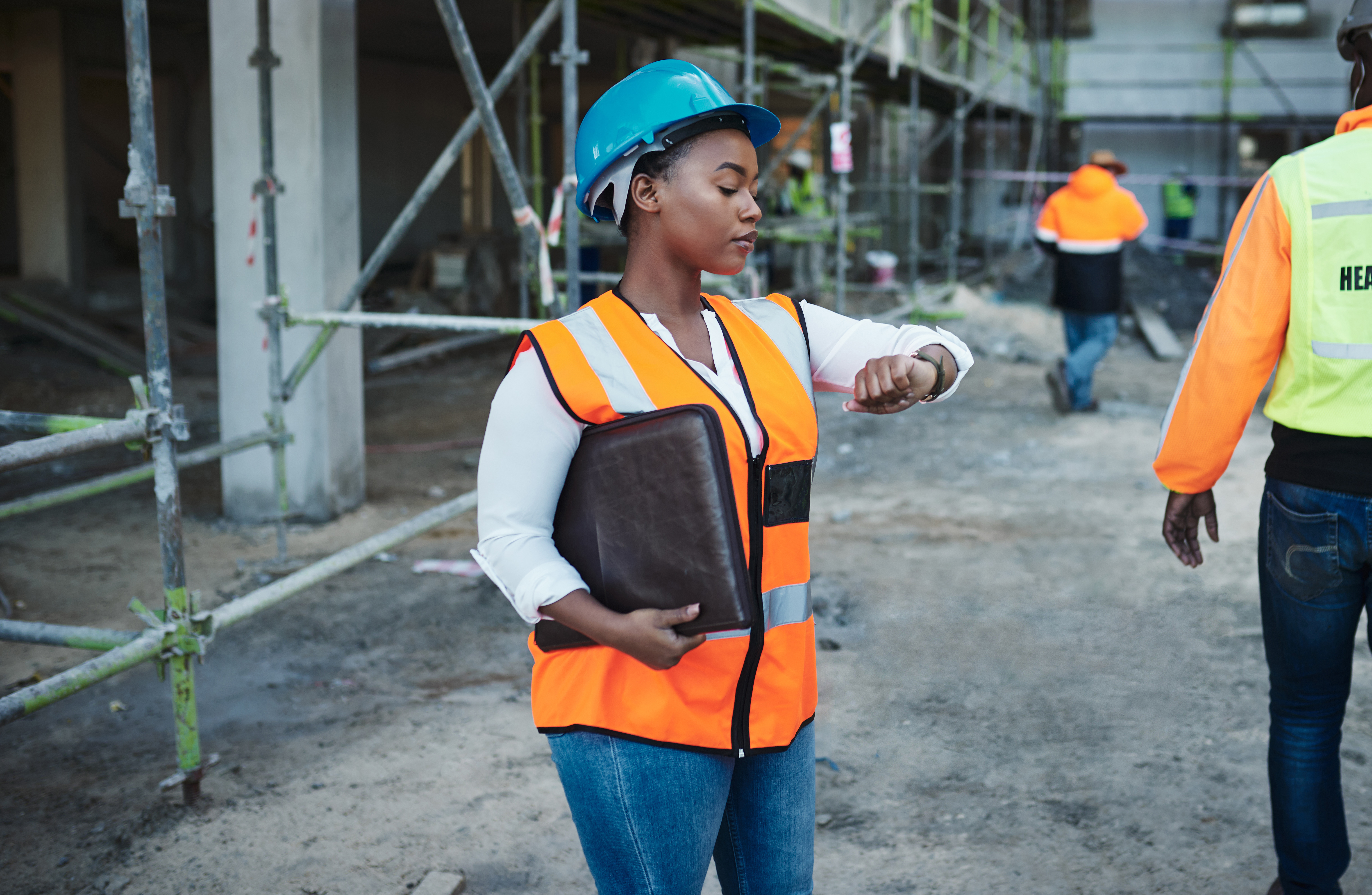 Photo d'une jeune femme vérifiant l'heure tout en travaillant sur un chantier de construction