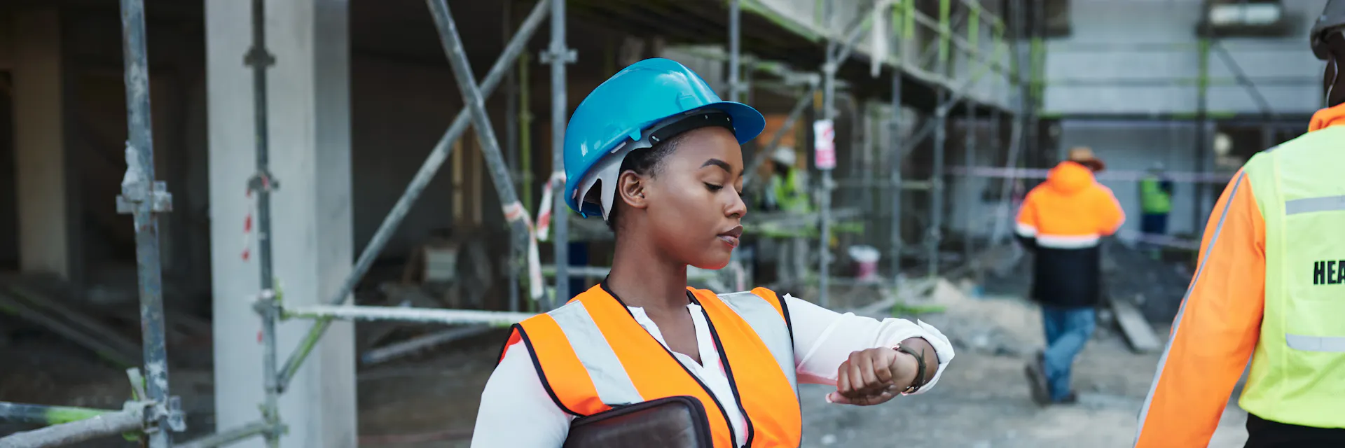 Photo d'une jeune femme vérifiant l'heure tout en travaillant sur un chantier de construction