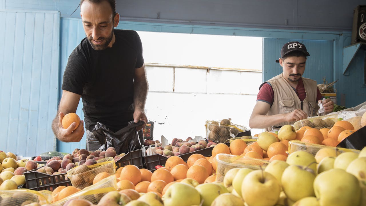 Abdel Halim al Qasir selects oranges to buy at a grocer’s inside Za’atari refugee camp.