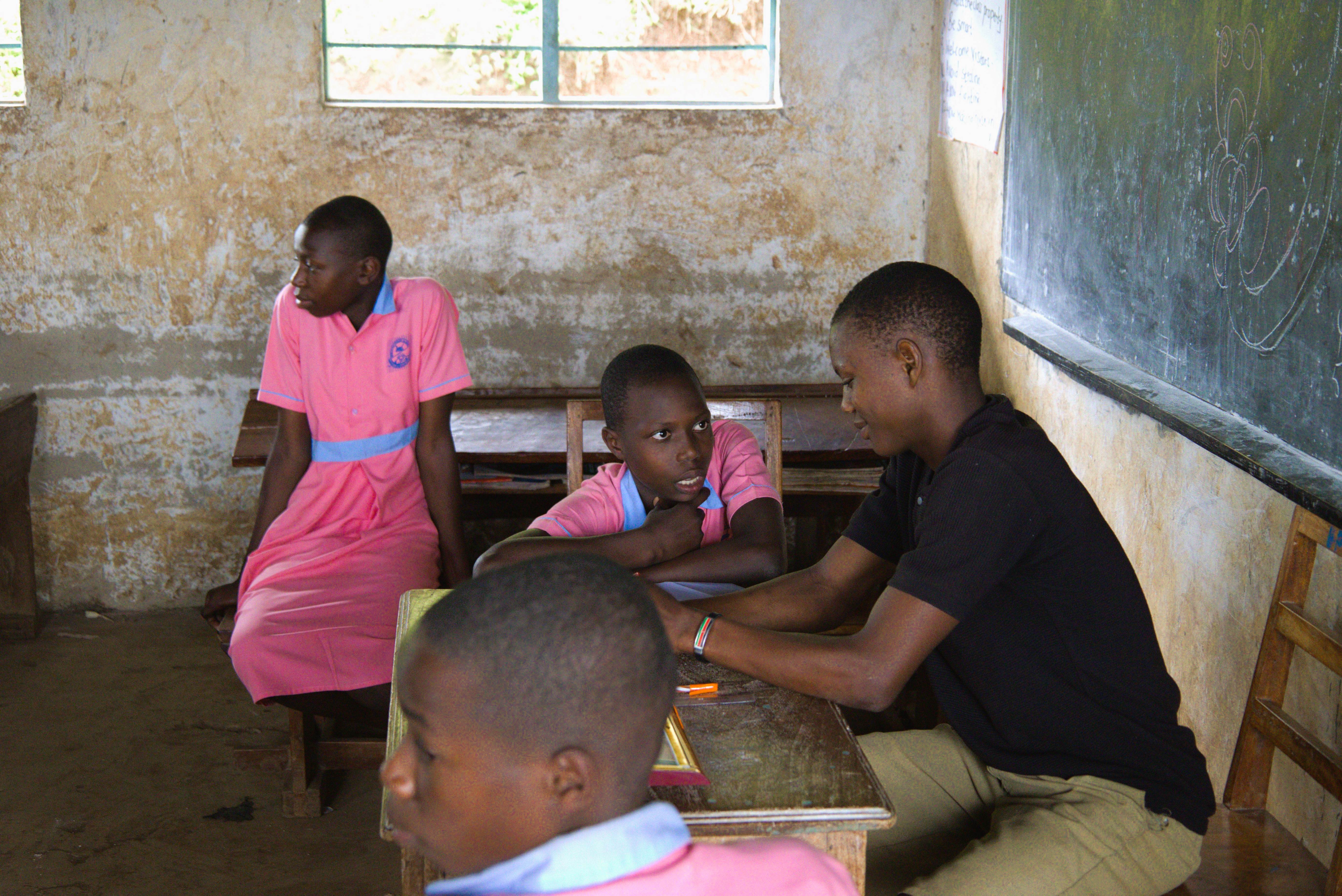 Rebecca Nakayega Wandegge's two daughters sit in a classroom with their teacher. (2025)