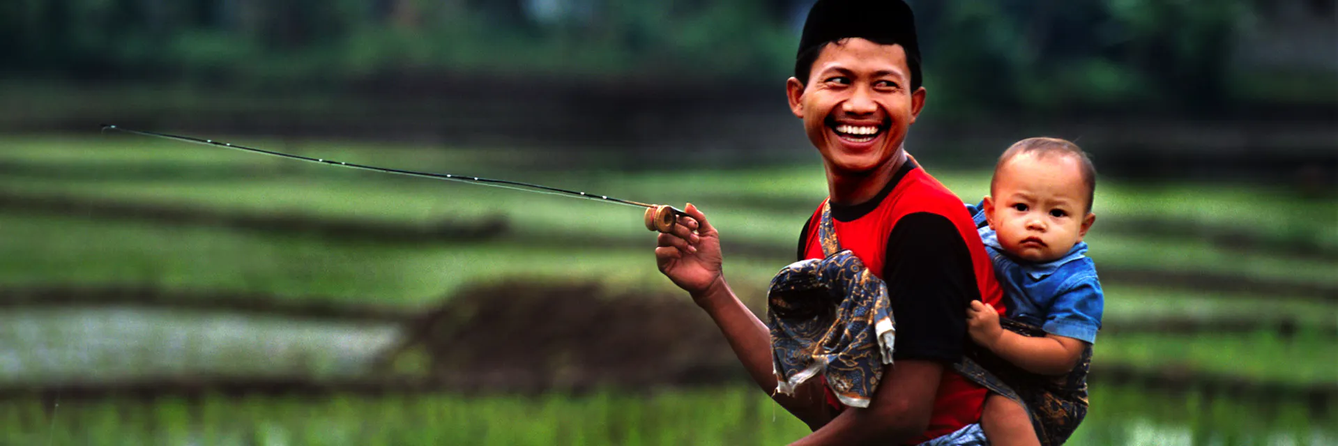 A father carries his child on his back while fishing. Jakarta. 2015.