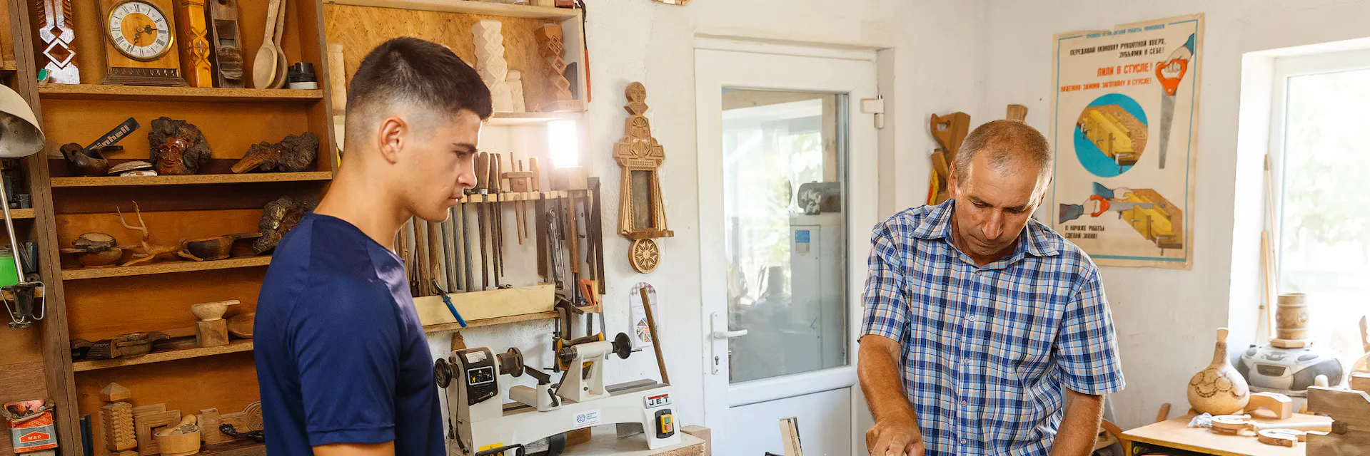 Two male workers, one young and one older, are cutting wood in the workshop. Cahul, Moldova.