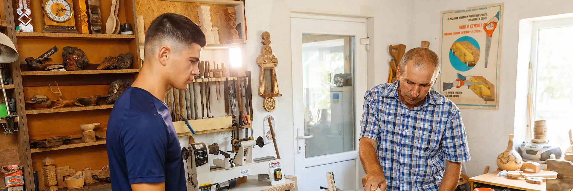 Deux ouvriers, l'un jeune et l'autre plus âgé, coupent du bois dans l'atelier. Cahul, Moldavie. 2020