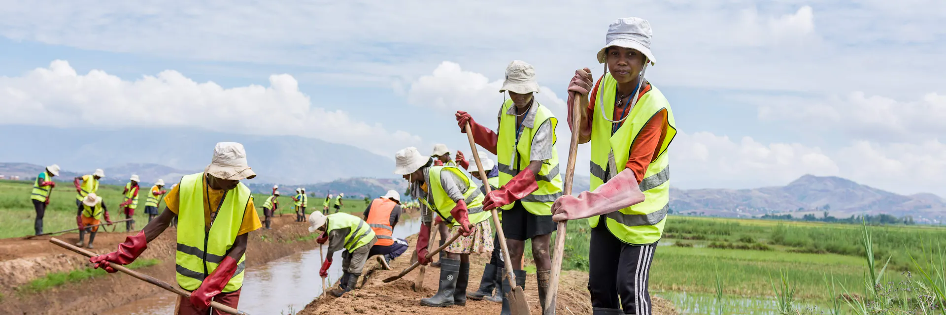 Workers wearing yellow jerseys and using long-handed tools work on the Ambondromisotra drain in Madagascar. (2025)