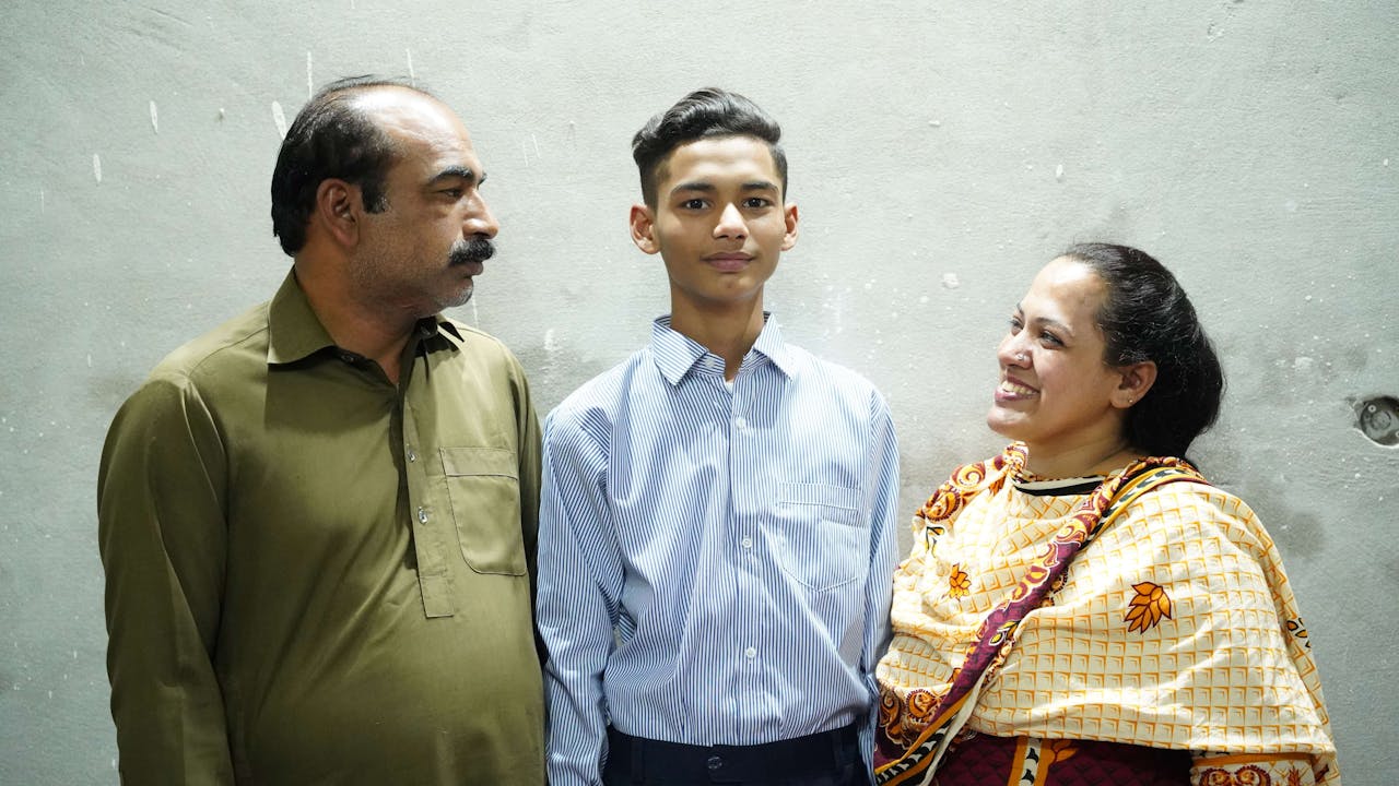 Shafique Massih y su esposa observan con cariño a su hijo adolescente, situado entre ellos.
