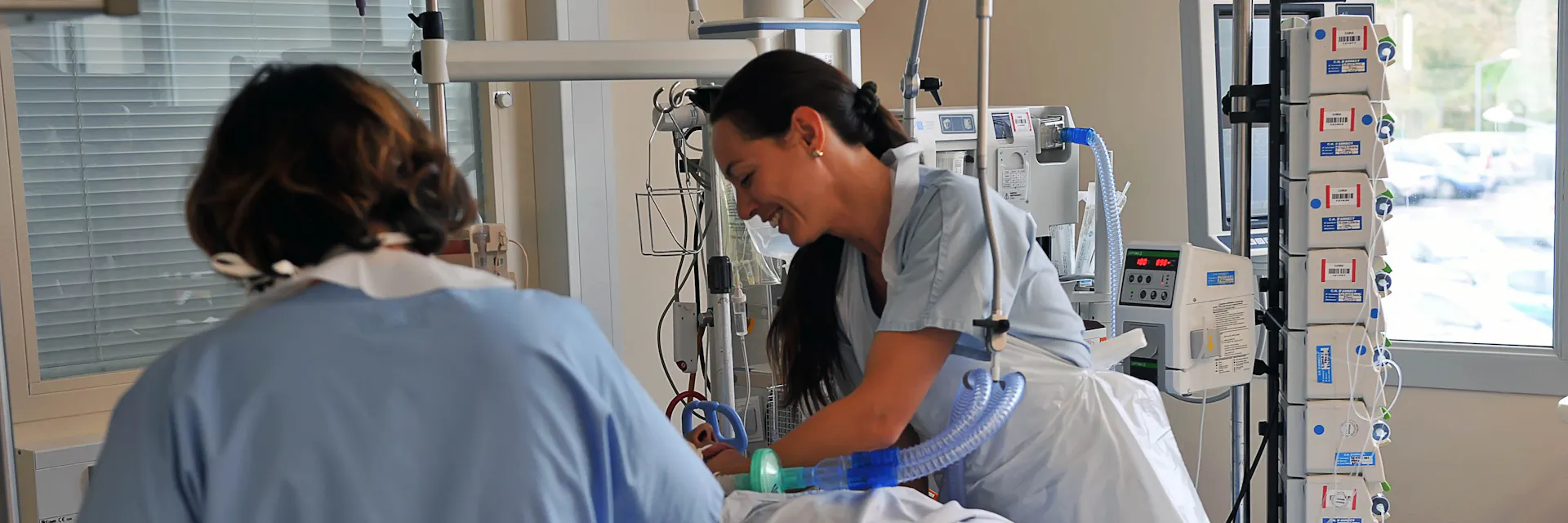 Nurses care for a patient who is lying in a hospital bed in an intensive care unit at the Centre Hospitalier de la Région d'Annecy (CHRA).
