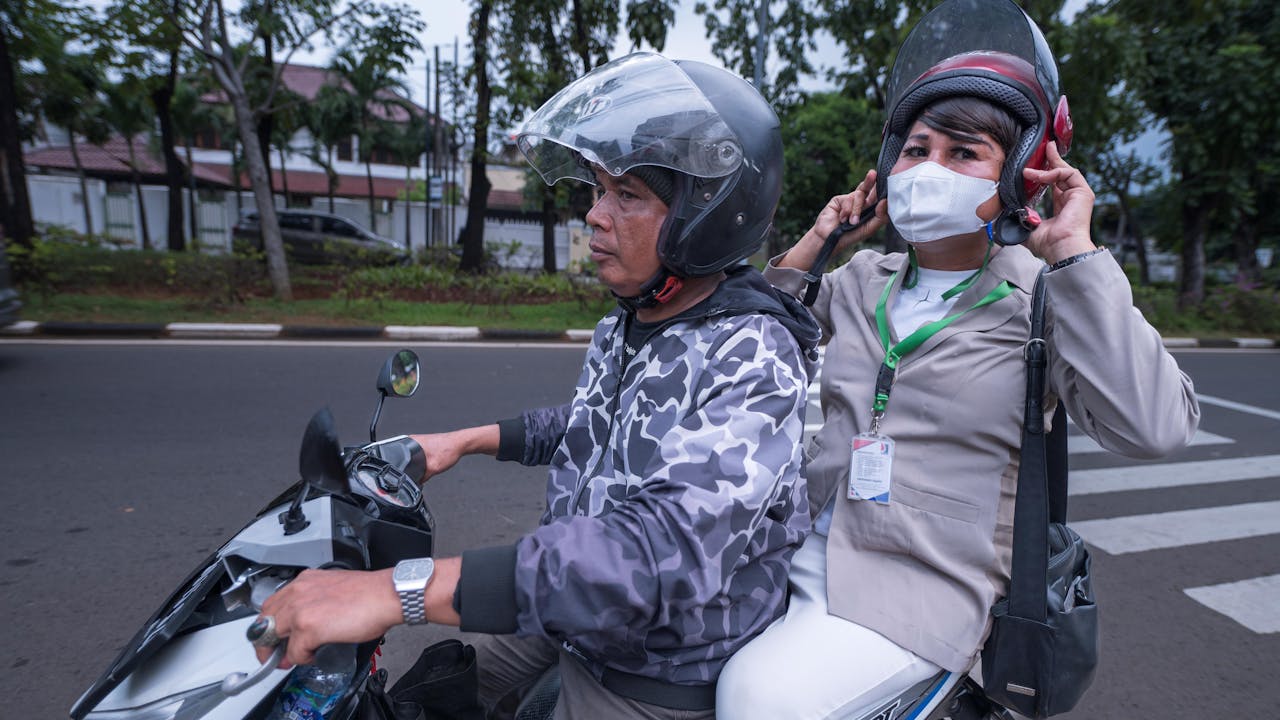 Echi se sienta en la parte trasera de un mototaxi y se pone el casco.