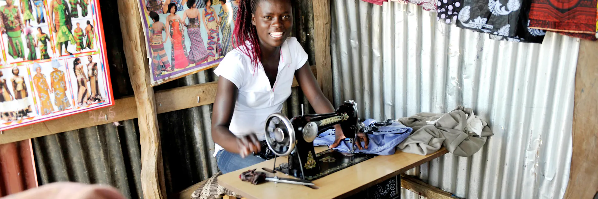 Jeune femme Jackline travaillant sur une machine à coudre dans sa petite boutique où elle fabrique du prêt-à-porter, district de Manyatta à Kisumu (Kenya), 2011