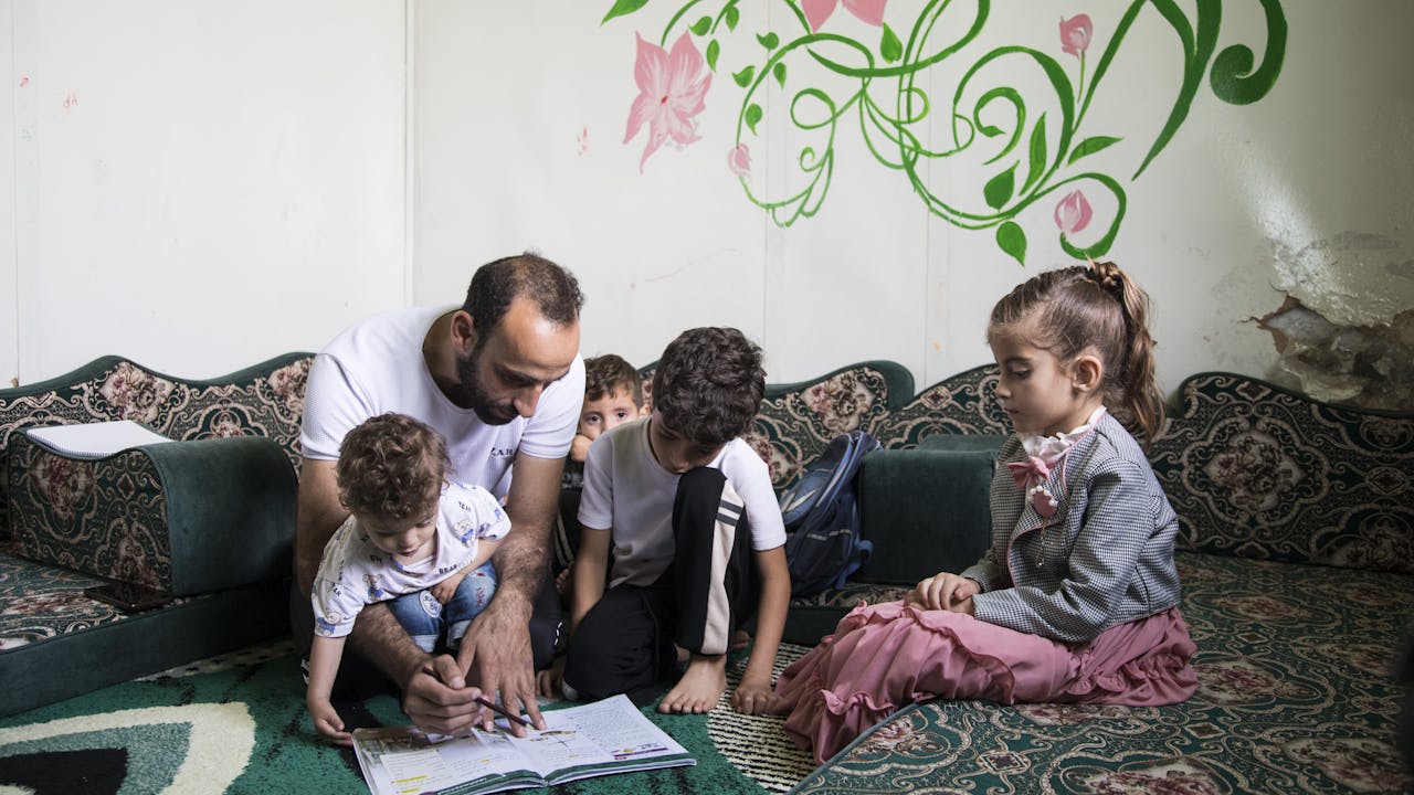 Abdel Halim al Qasir sentado con sus cuatro hijos en el refugio donde vive en el campo de refugiados jordano de Za'atari.