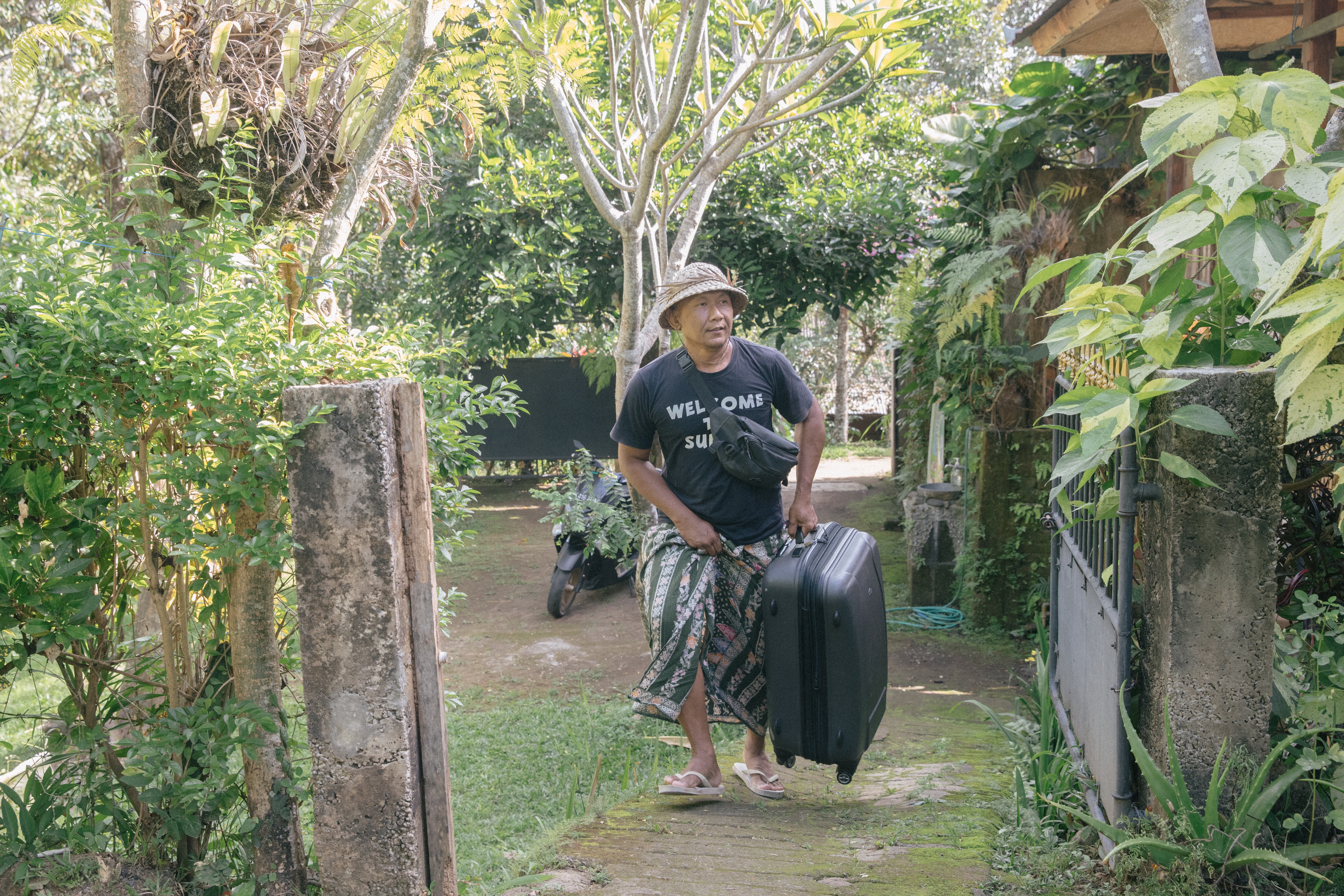 Dekha Dewandana carries a suitcase at the entrance to his homestay.