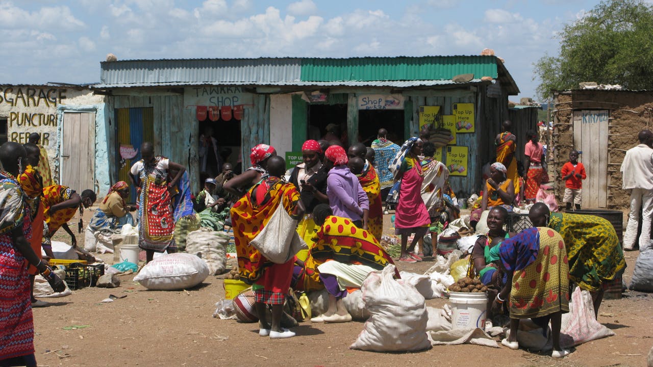 Día de mercado en una aldea masái. Muchas masái reunidas comprando y vendiendo alimentos, como patatas.