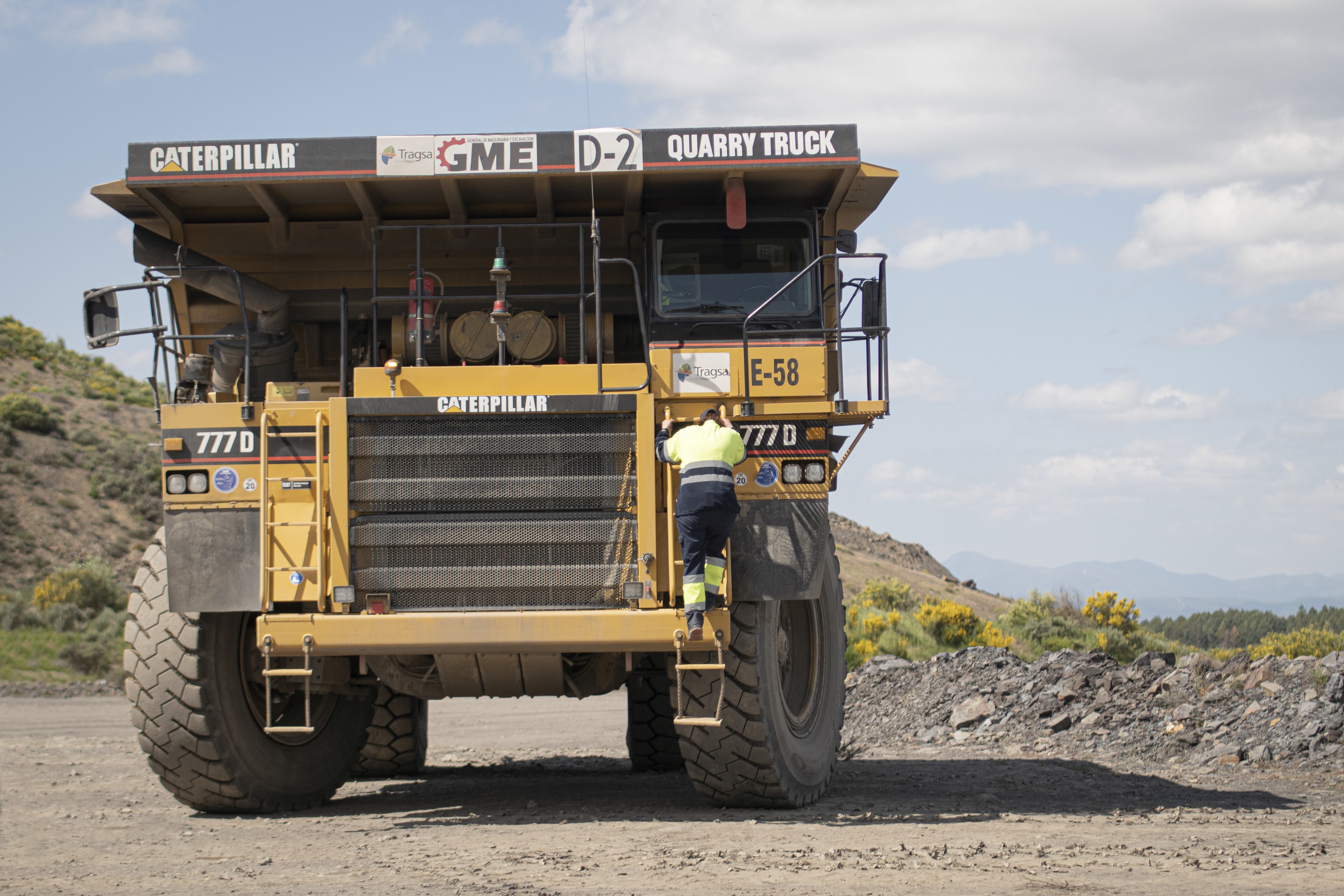 Cristina Carro grimpe à l'échelle à l'avant d'un camion de carrière pour accéder au siège du conducteur.