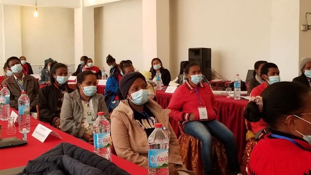 Domestic workers in a meeting room, wearing masks.