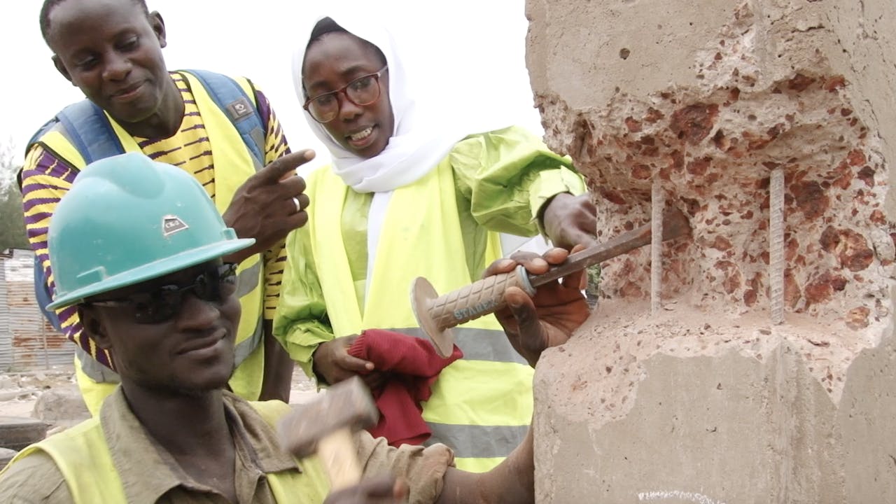 Three workers discuss how to repair a wall at the construction site.