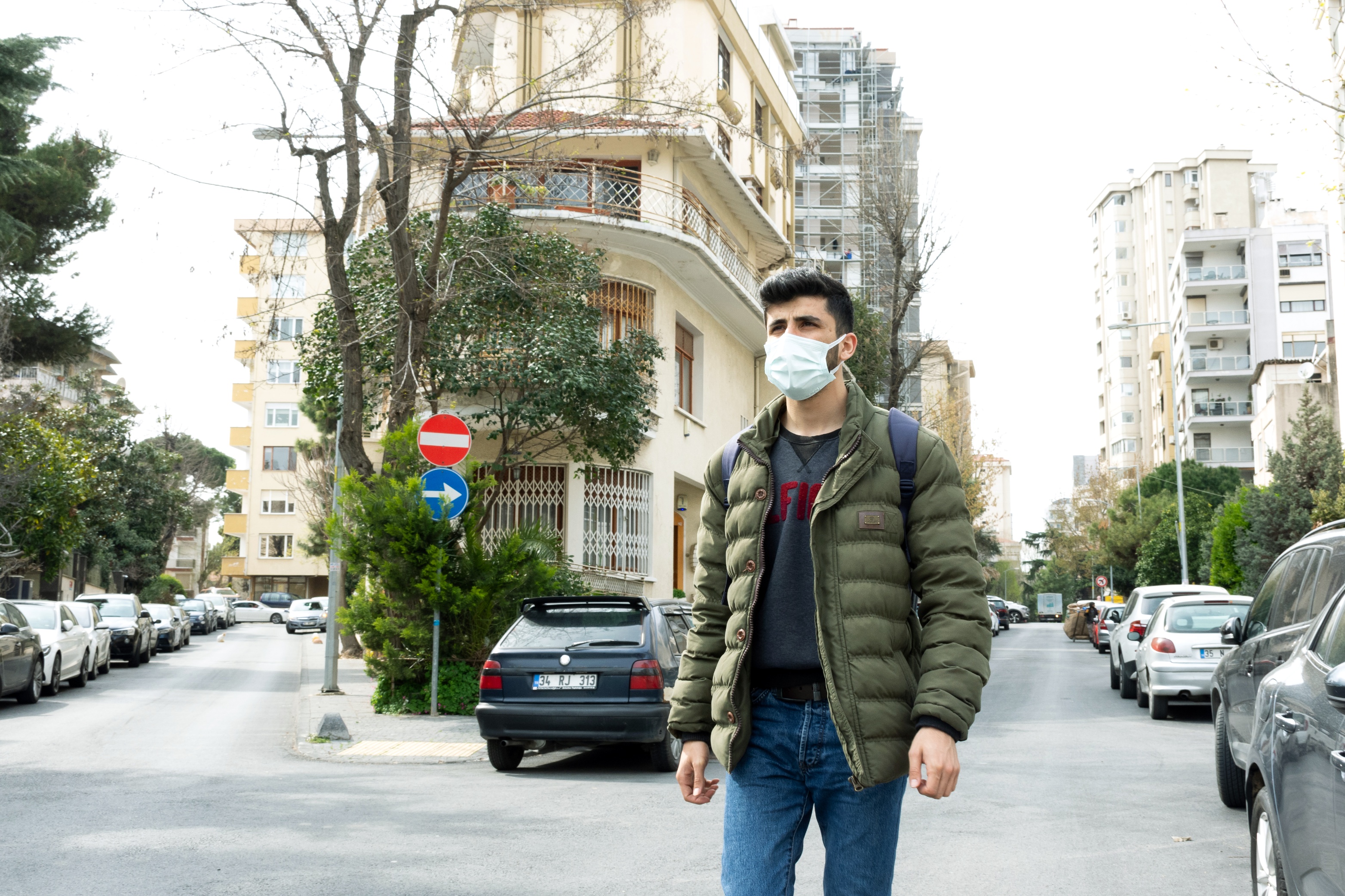 Morshed Ali walks along a city street in Turkey. He wears a face mask.