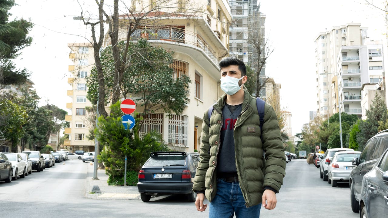 Morshed Ali walks along a city street in Turkey. He wears a face mask.