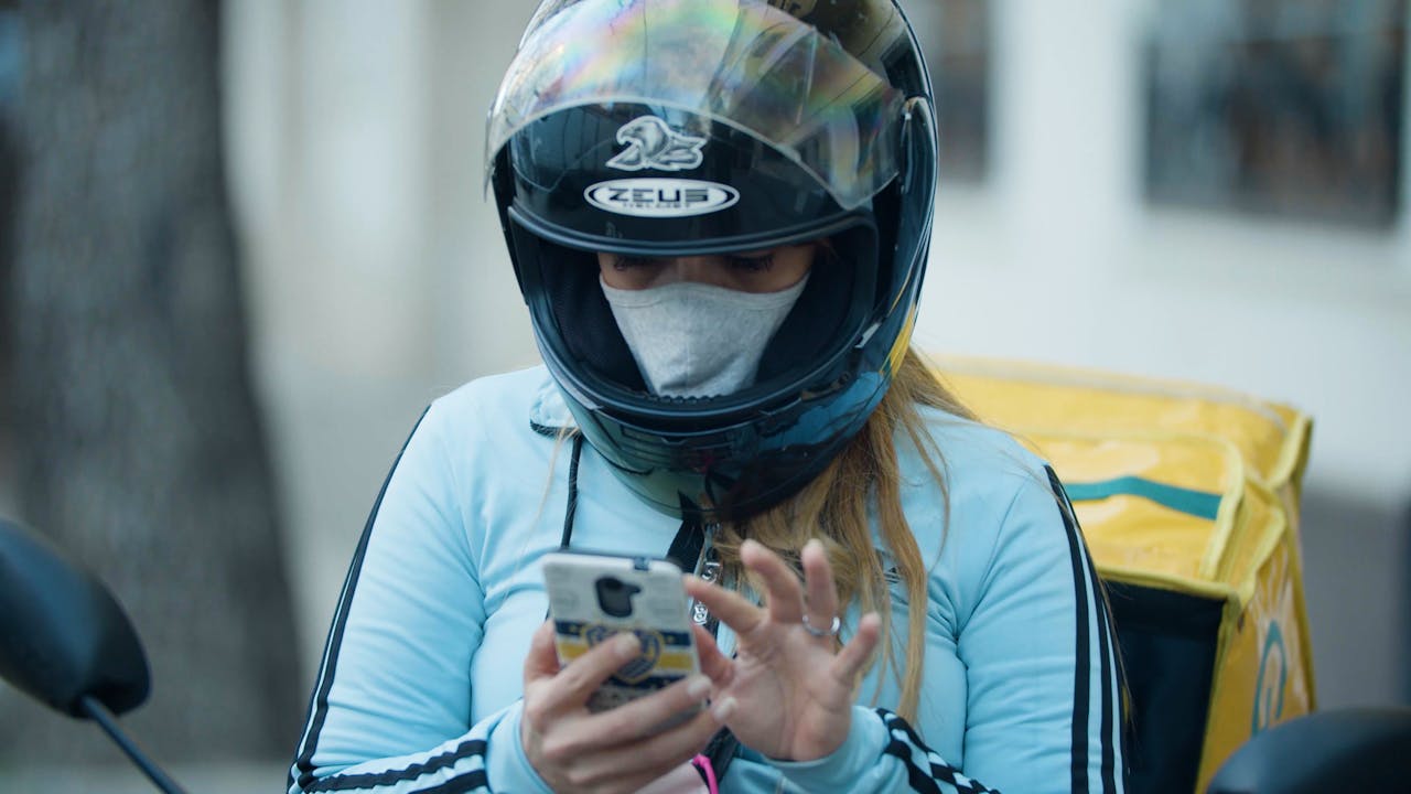 María Belén Fierro's sits on her motorbike checking her phone