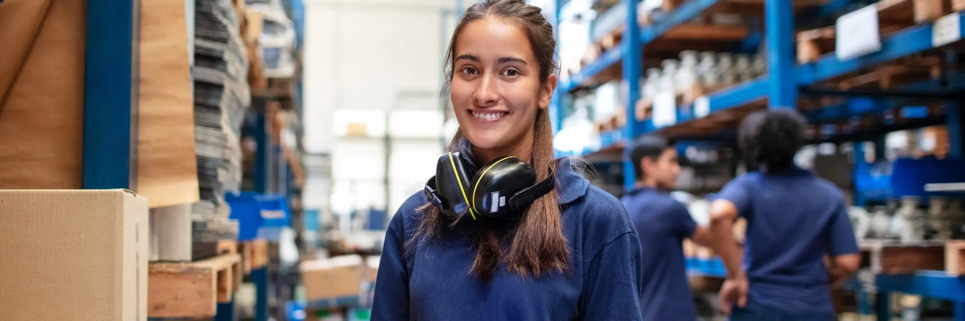 Portrait d'un ouvrier d'usine avec une tablette numérique regardant la caméra et souriant. Employé d'entrepôt avec des gens en arrière-plan.