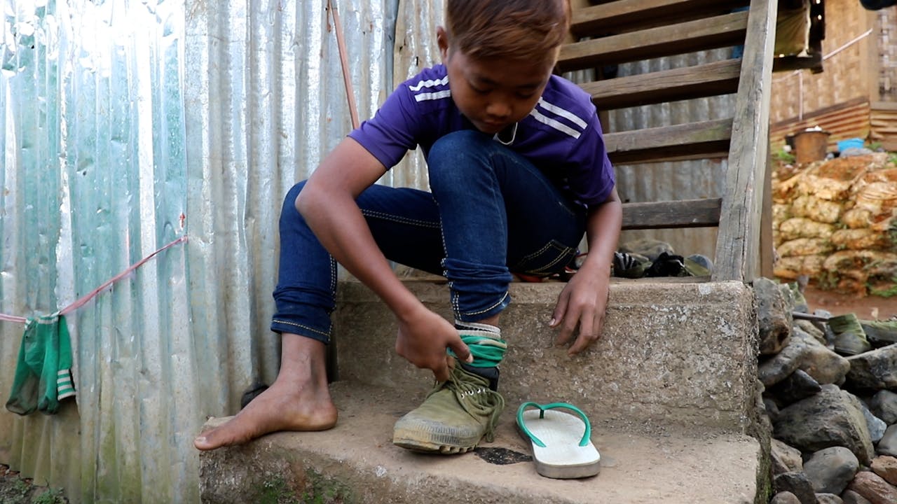 Min Min puts his shoes on in preparation to go jade scavenging.