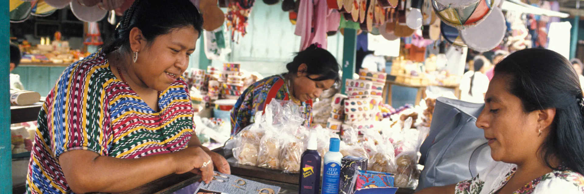 Una representante de ventas muestra sus productos a un vendedor del mercado maya indígena en Antigua, Guatemala.