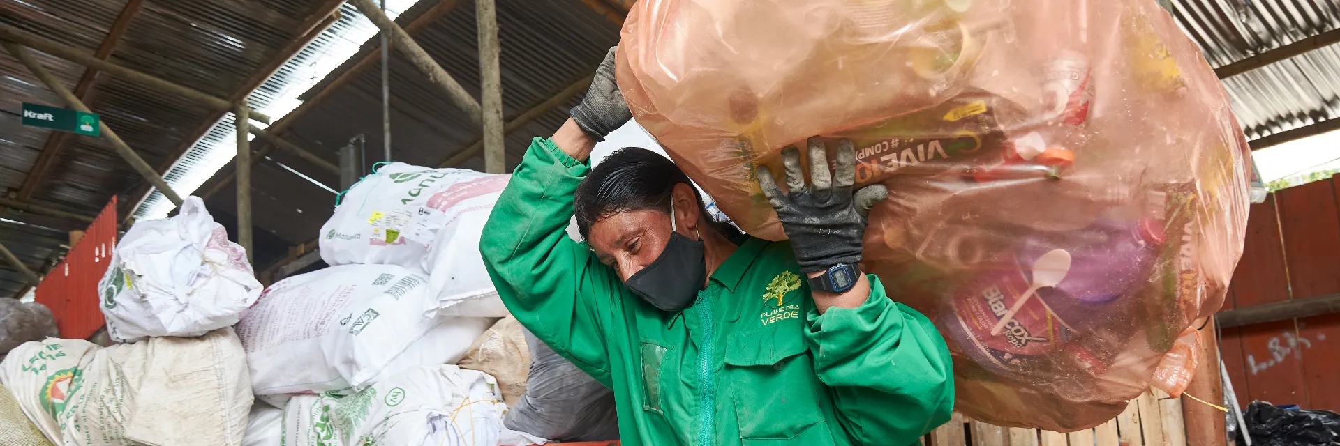 Un trabajador de una cooperativa de reciclaje lleva una bolsa de residuos en un almacén de reciclaje.