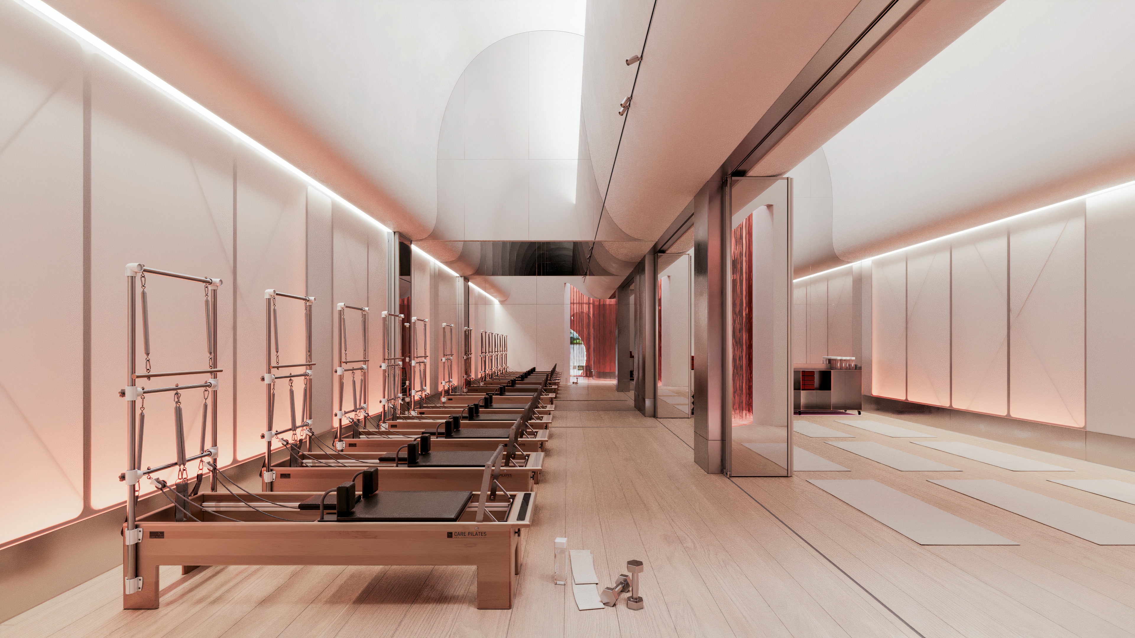 Luxury reformer Pilates studio with arched ceiling design, wooden flooring, mirrored walls, and coral accents