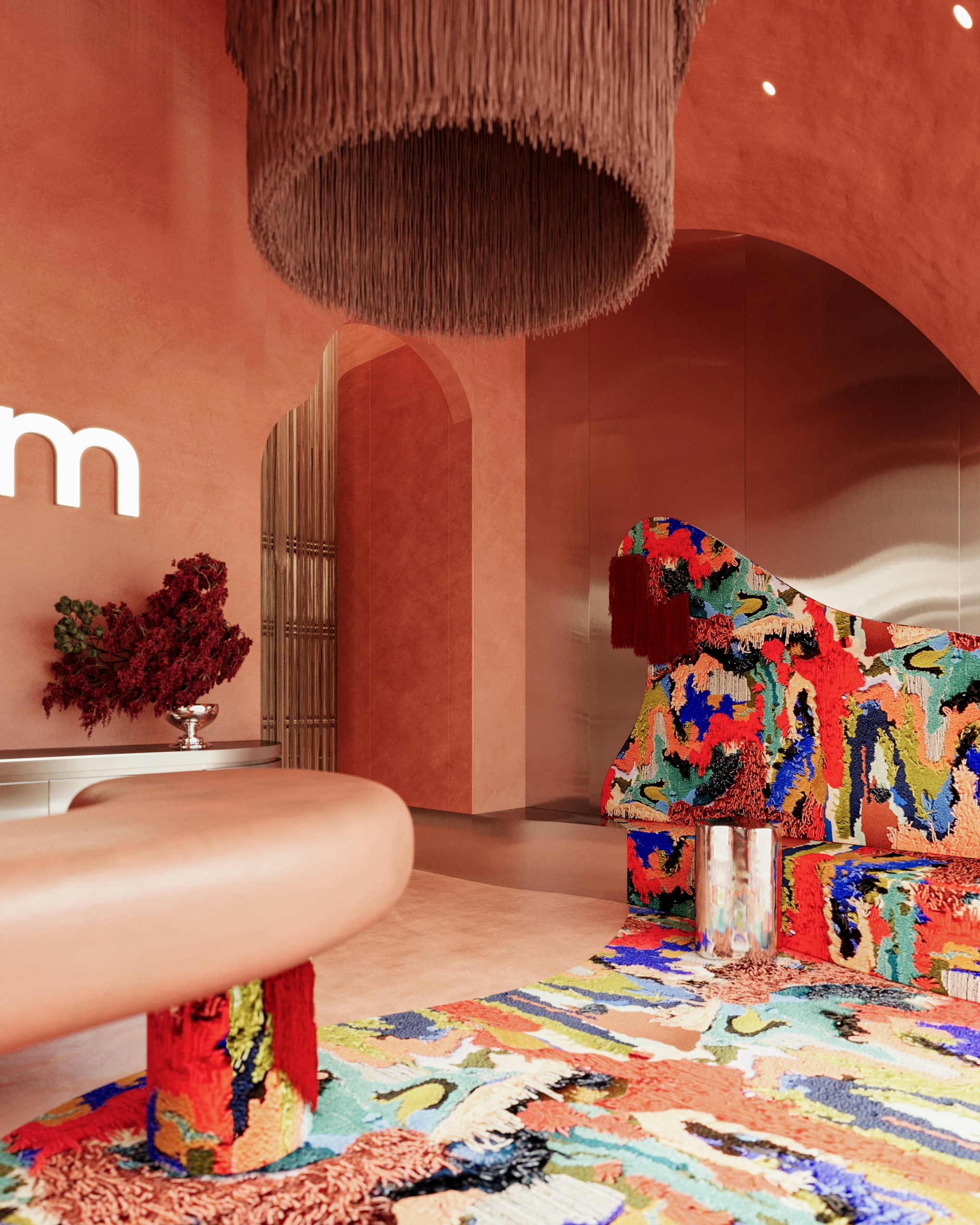 Modern reception area with coral plaster walls, sculptural furniture, fringe pendant lighting, and bold multicolor patterned rug