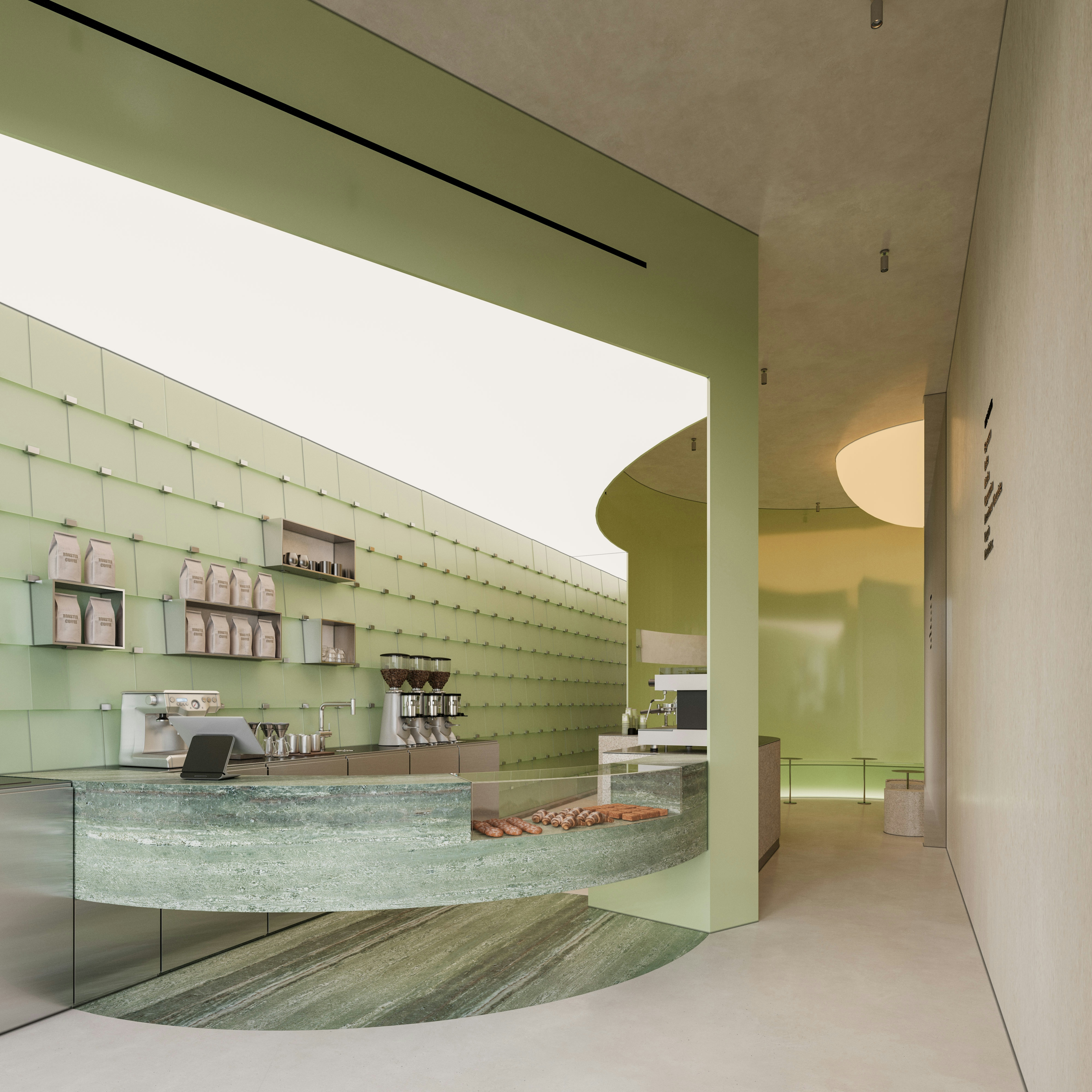 Café interior showcasing the sculptural green stone bar as the heart of the space, with the preparation area fully visible and treated as an architectural feature that interacts with light and material.