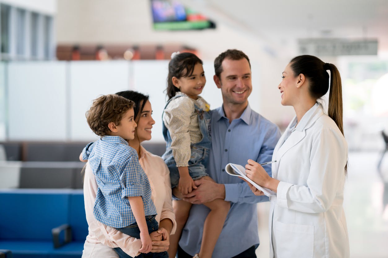 A doctor talking to extended family members in a hallway.