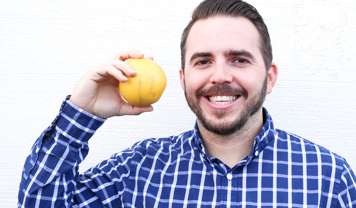 Carlos smiling and holding up a golden apple.