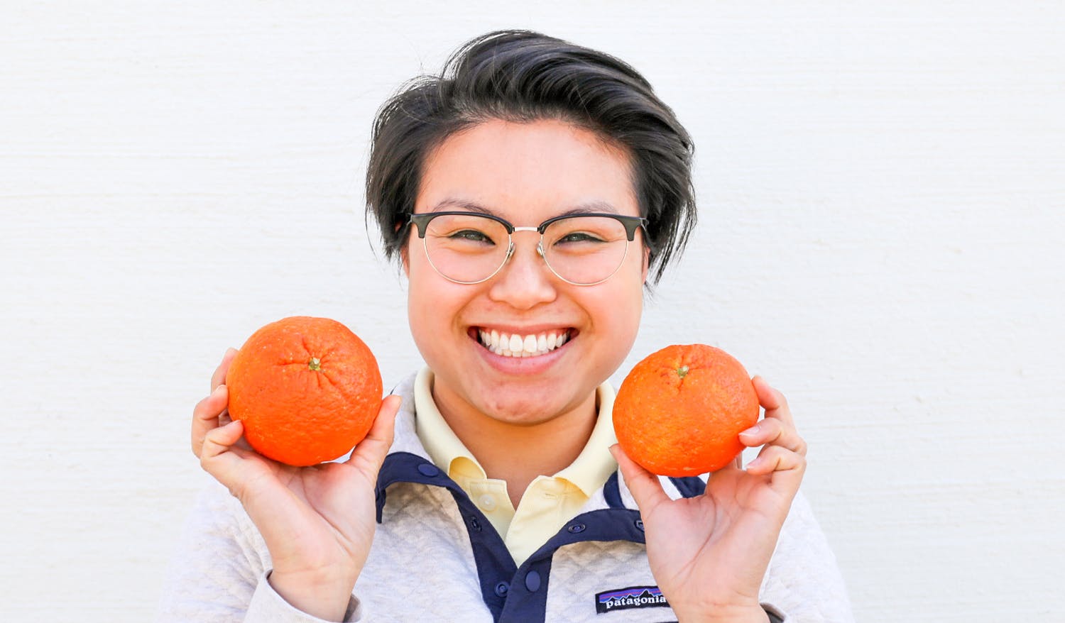 Marie smiling and holding up two oranges.
