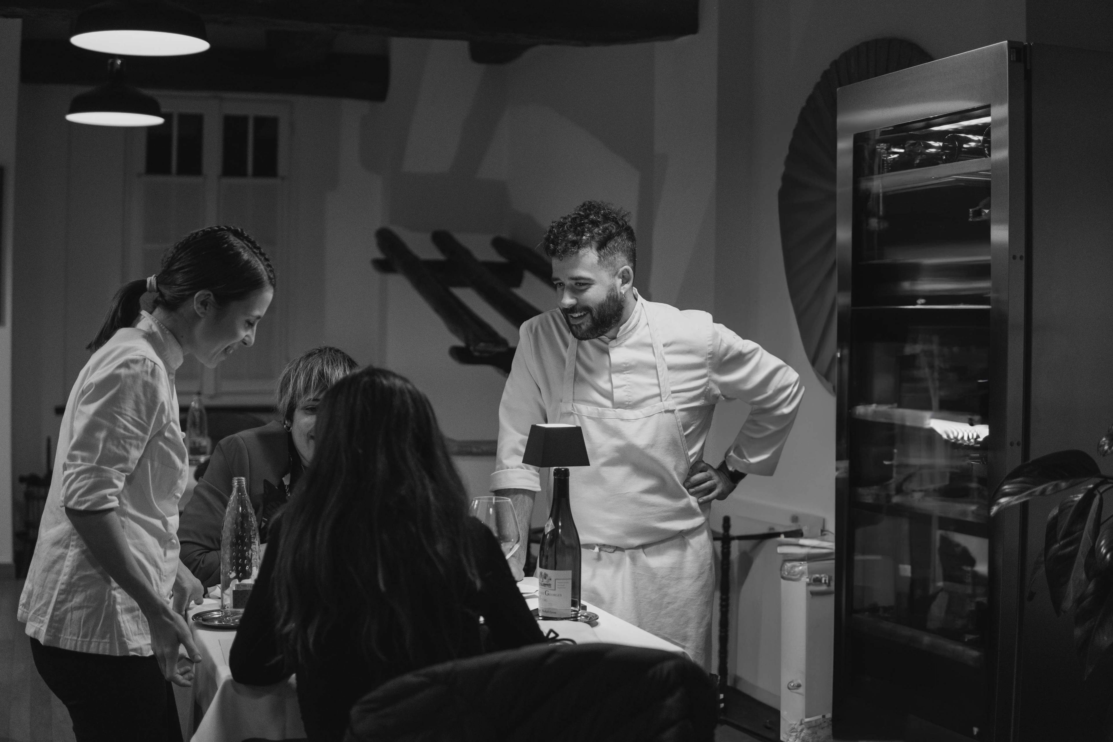 Gabriel Cinque e Valeria Loi, chef e founder di Impronta, sorridono e parlano con due clienti dopo una cena a domicilio.