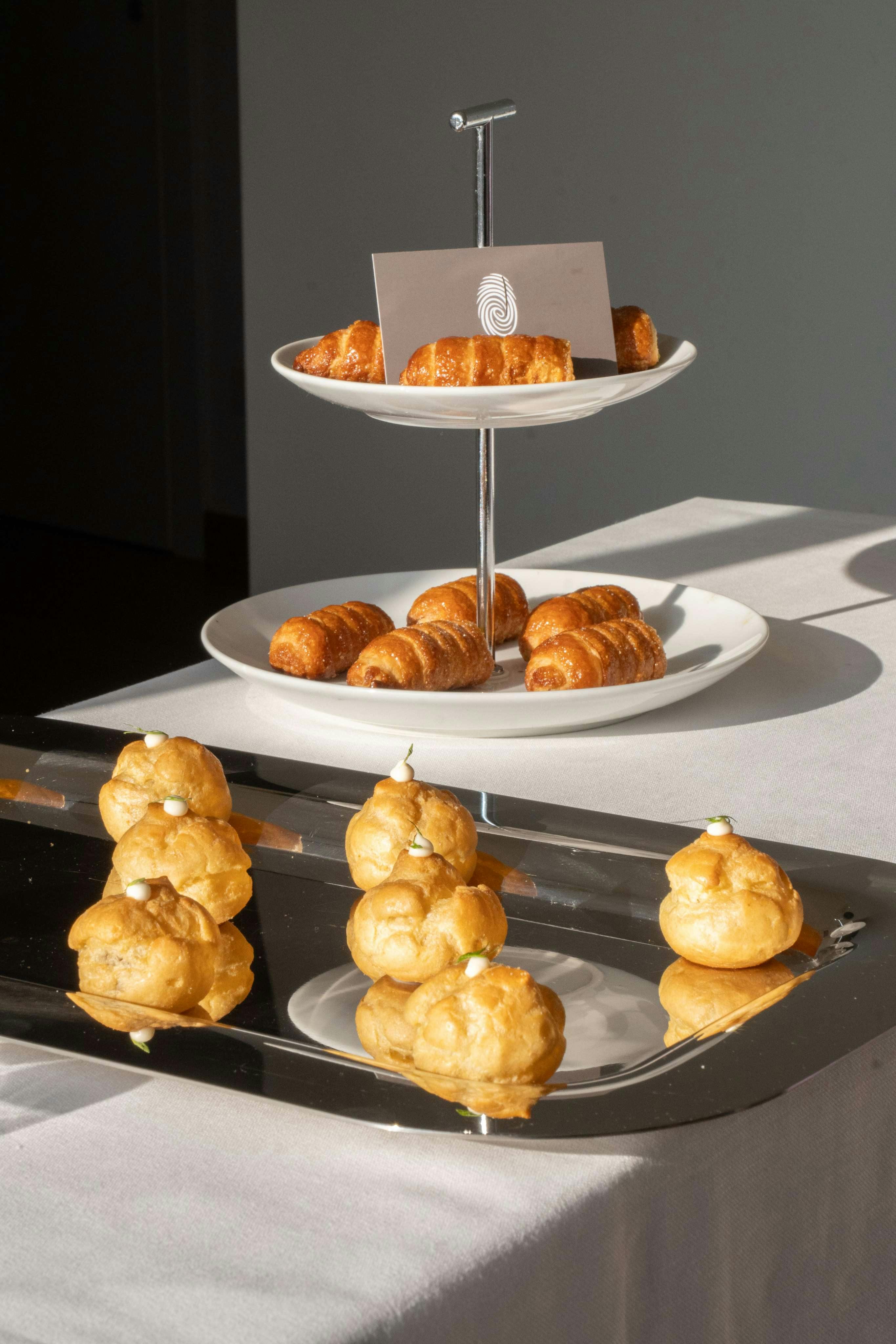 Buffet con tovaglia bianca su cui sono appoggiate alcune proposte di finger food di Impronta.