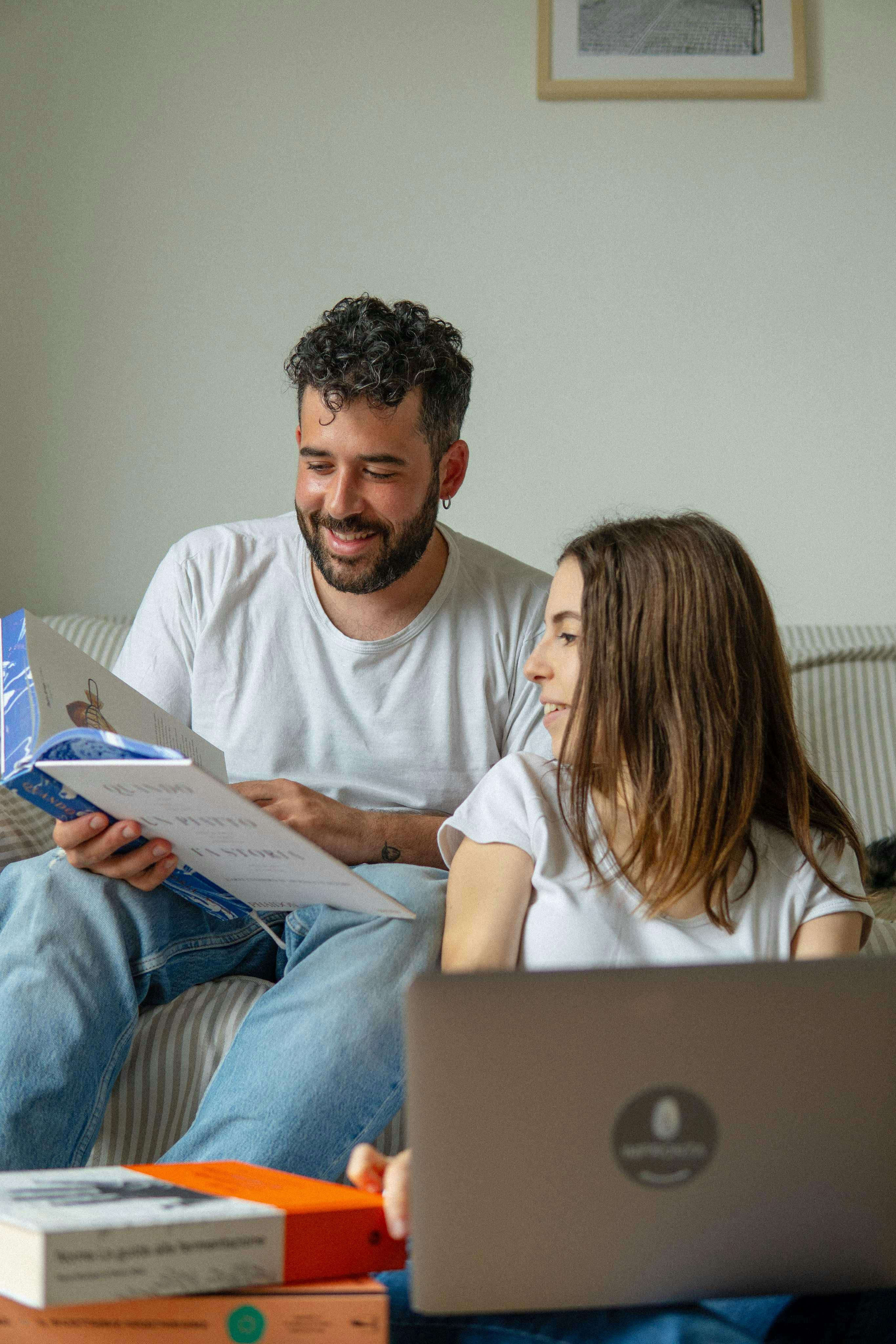 Nella foto ci sono Gabriel Cinque e Valeria Loi, chef e founder di Impronta, che sfogliano sorridendo un libro di cucina.