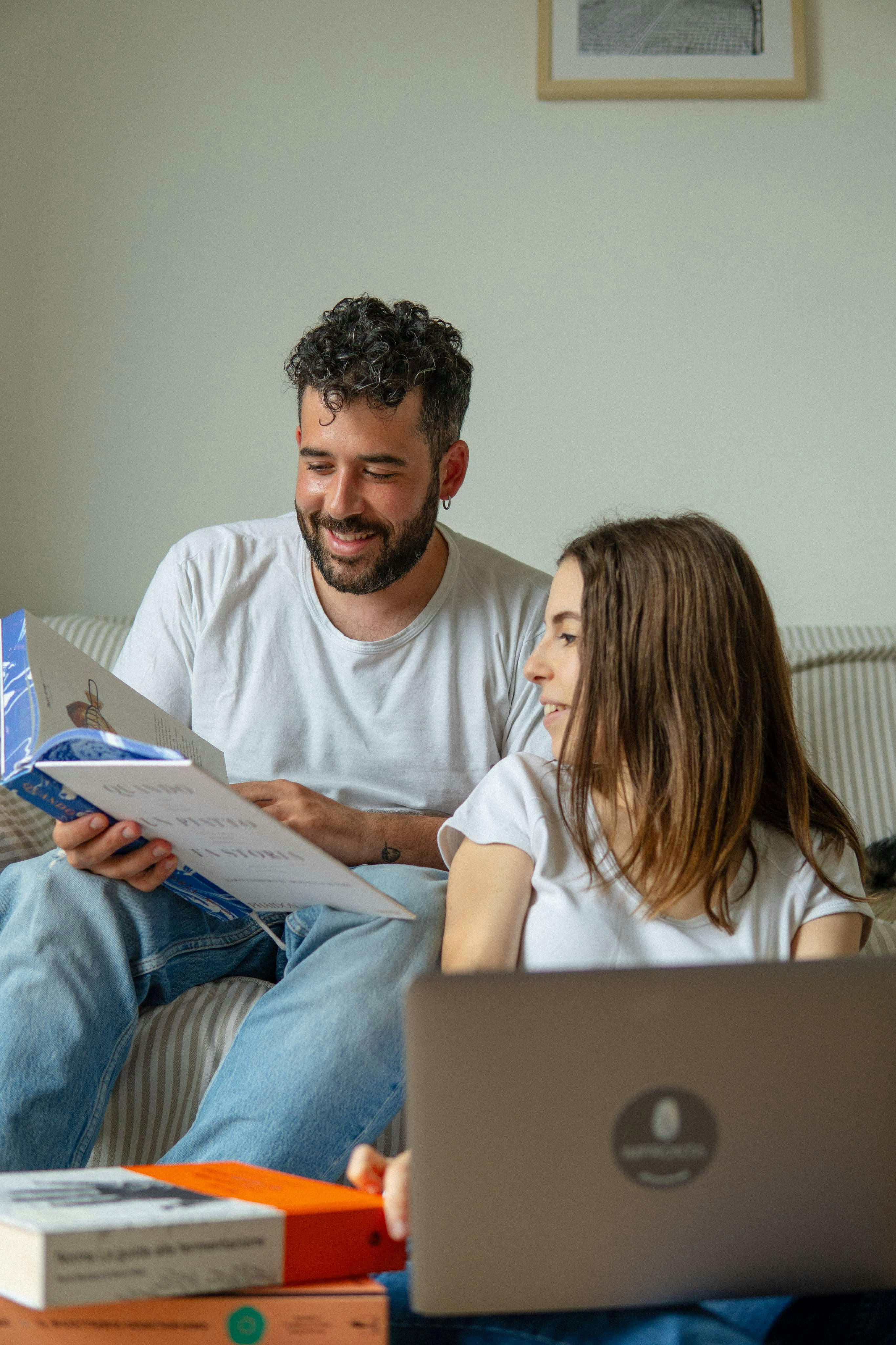 Nella foto ci sono Gabriel Cinque e Valeria Loi, chef e founder di Impronta, che sfogliano sorridendo un libro di cucina.