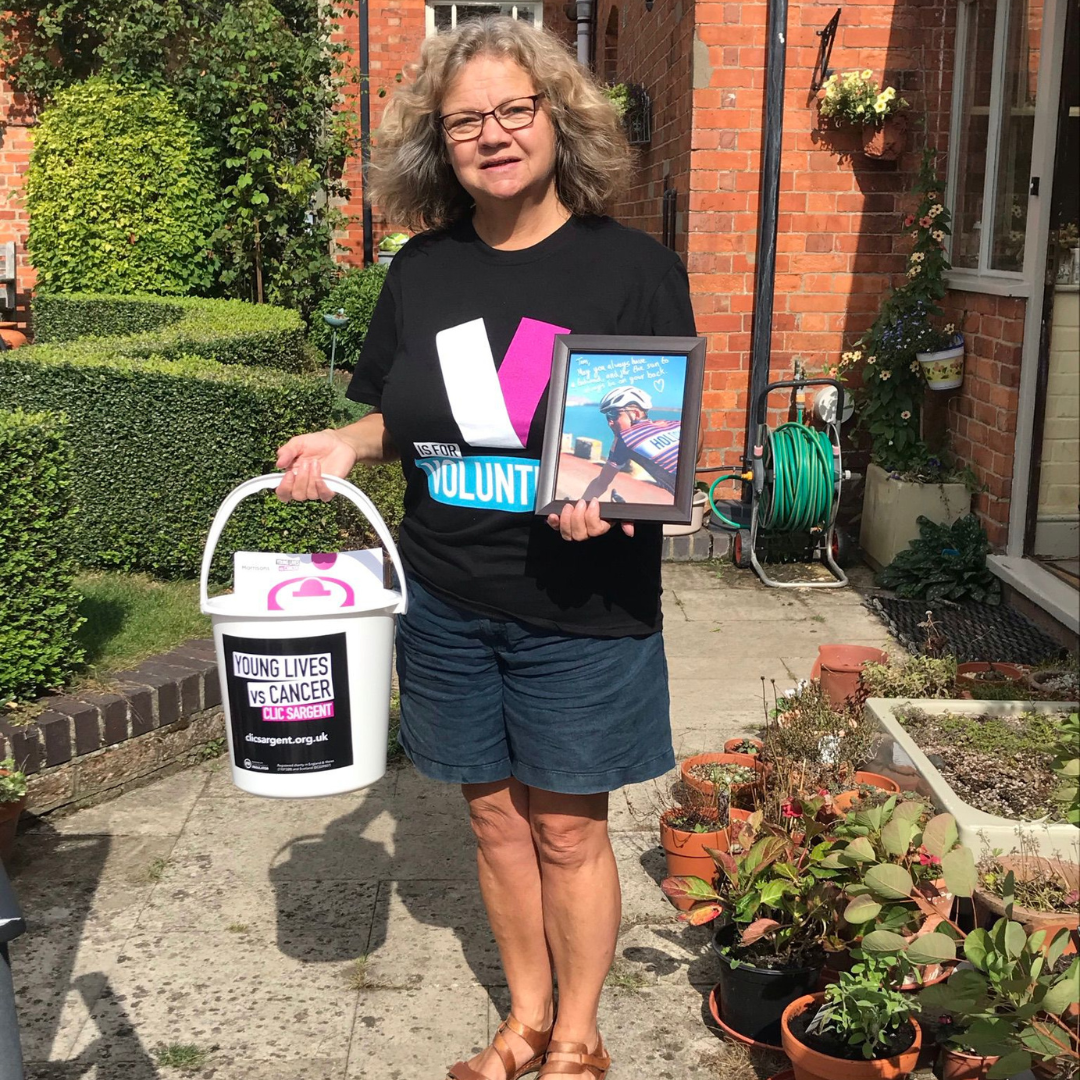 Janet James posing with photo of Tim and bucket for collection