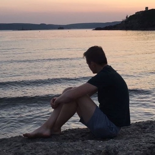 James sitting on a beach watching the sunset