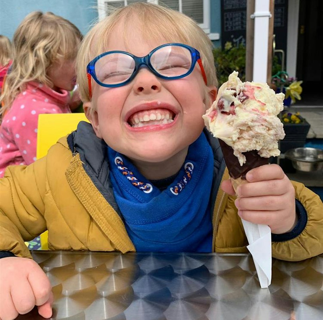 Larsen, wearing blue glasses, giving a big grin to the camera and holding a ice cream
