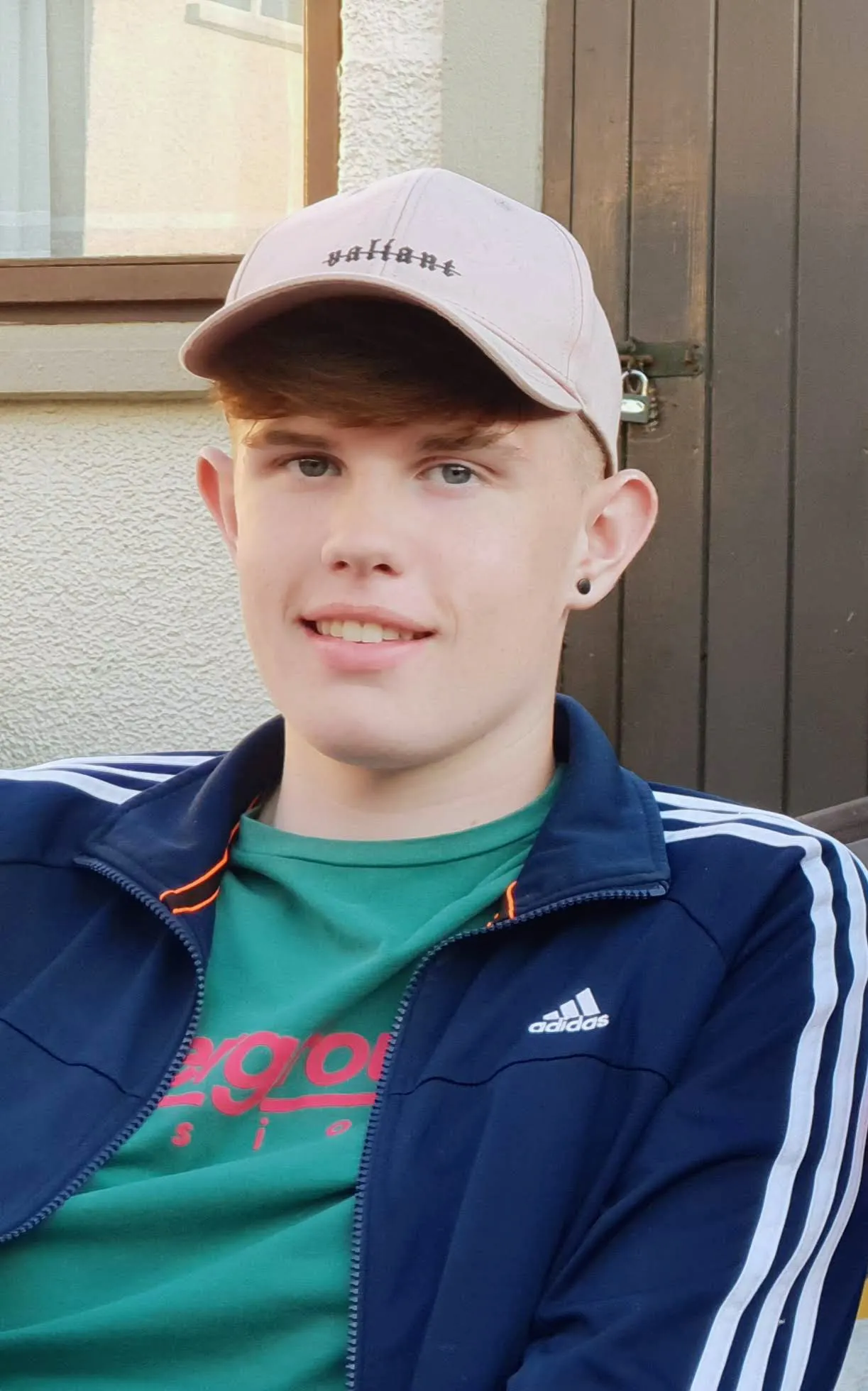 Oran smiling wearing a grey cap and navy jacket.