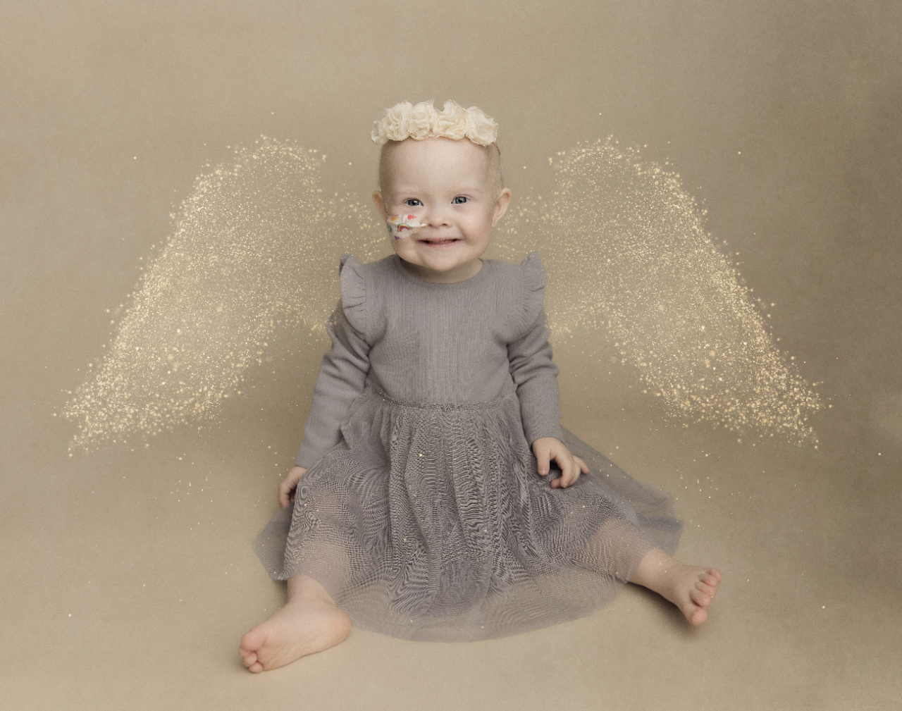 Ava sat smiling at the camera with angel wings behind her
