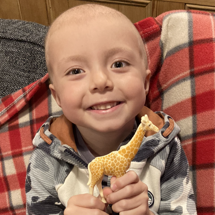 Ollie smiling at the camera holding toy giraffe