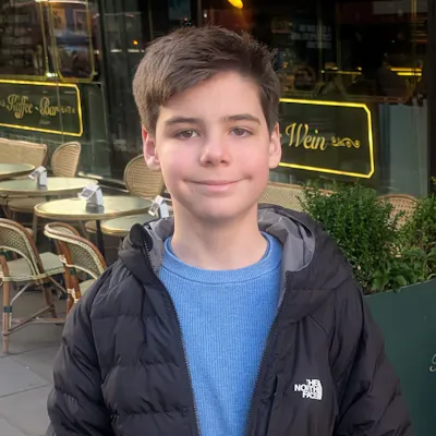 Jack wearing a blue t shirt and dark coat outside a cafe.