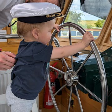 Eddie steering a boat in a sailors cap