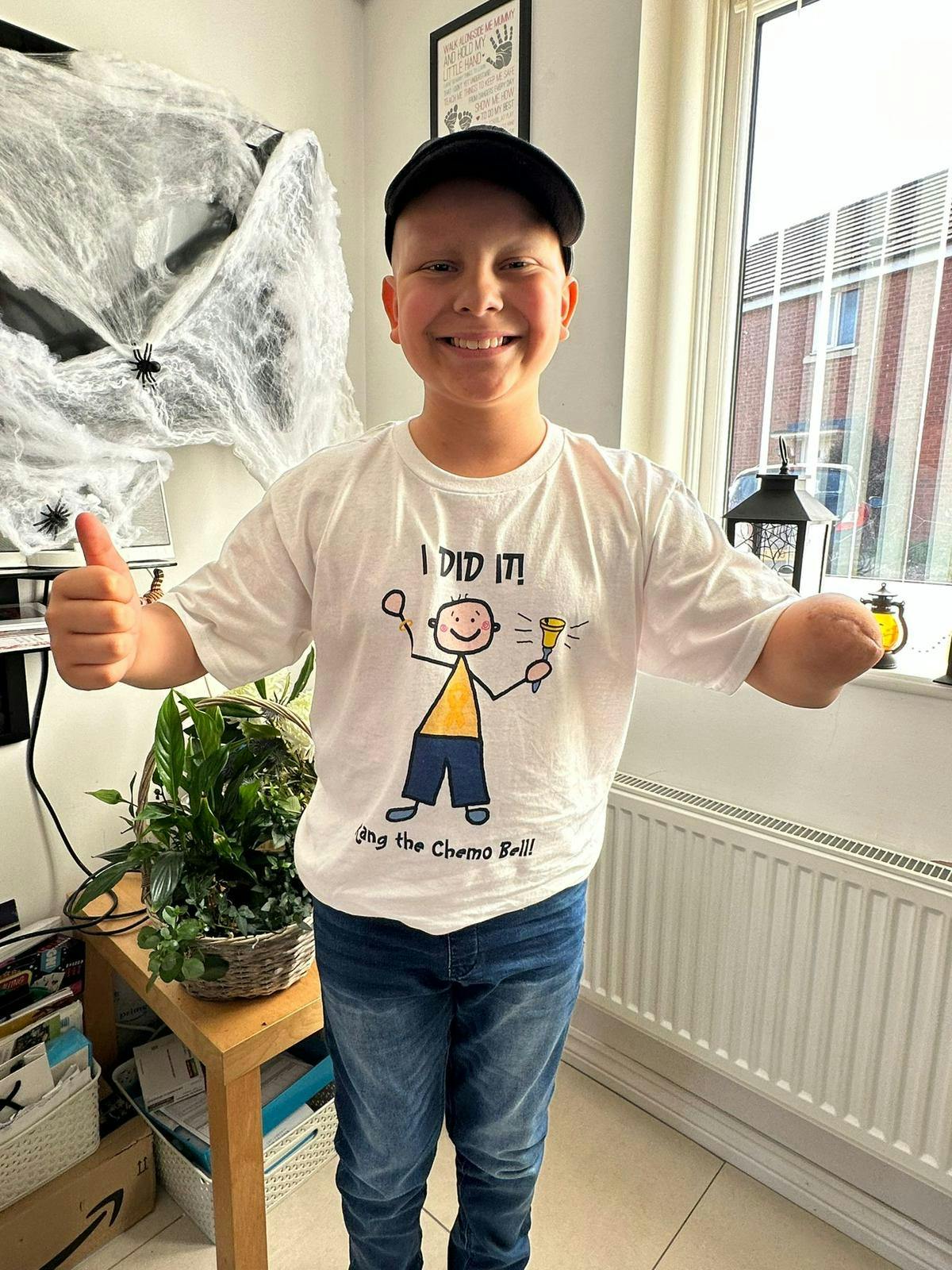 A photo of Rian in a black cap and white t-shirt that says "I did it!" smiling for the camera.